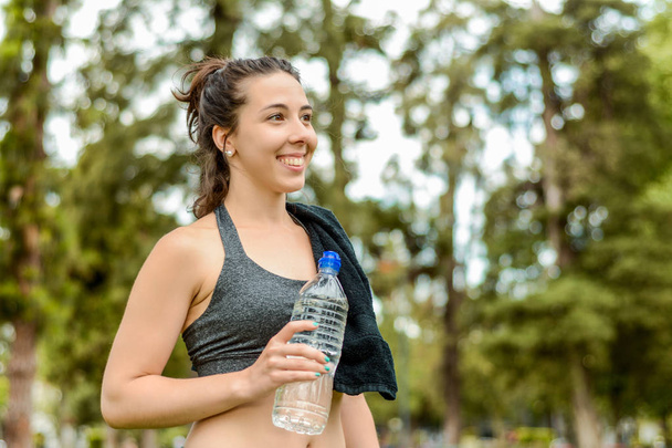 Portrait of sportswoman drinking water after workout. Outdoors - Photo, Image