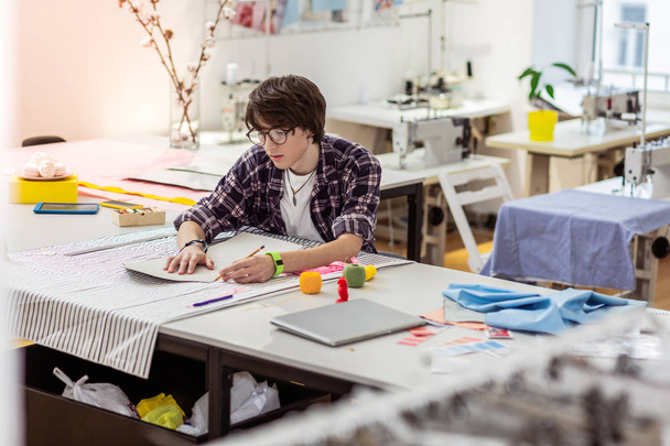 Young dark-haired asian designer with a green watch working in a studio - Valokuva, kuva