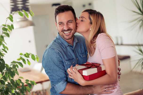 Beautiful young couple celebrating at home.Man giving gift to his girlfriend. - Φωτογραφία, εικόνα