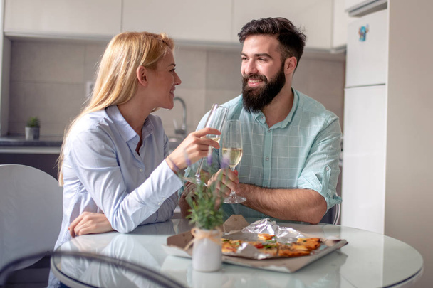 Νεαρό ζευγάρι έχοντας μεγάλο χρονικό διάστημα στο σπίτι, τρώγοντας πίτσα και κρασί. - Φωτογραφία, εικόνα