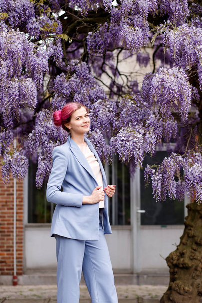 Gentle refined woman in the garden of beautiful wisteria trees. - Photo, Image