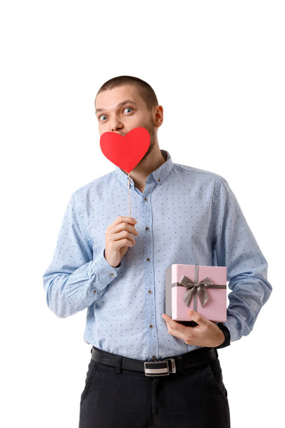 Young happy man holding red paper heart and gift box isolated on white background - Фото, изображение