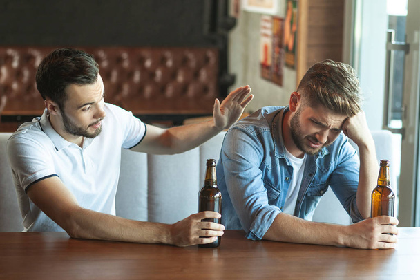 sad drunk man drinking beer his friend in cafe together - 写真・画像