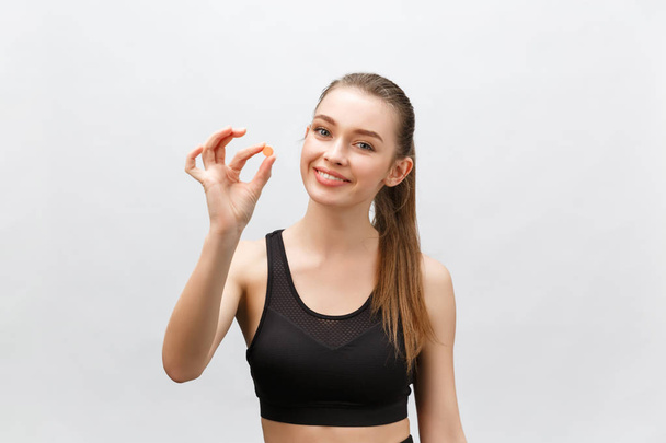 Supplements, Sports, Vitamins, Diet, Nutrition, Healthy Eating, Lifestyle. Close up of smiling fitness woman taking pill with cod liver oil Omega-3 , vitamin D, E, A fish oil capsules. - Photo, Image