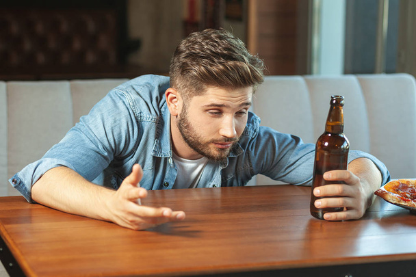 drunk man sitting at the table in the cafe drinking beer - Photo, Image