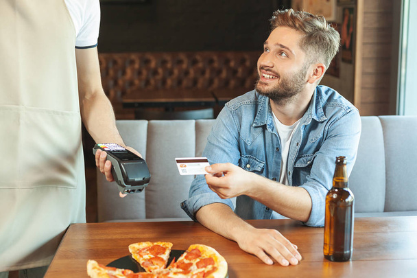 smiling man paying with credit card in the cafe - Foto, Bild
