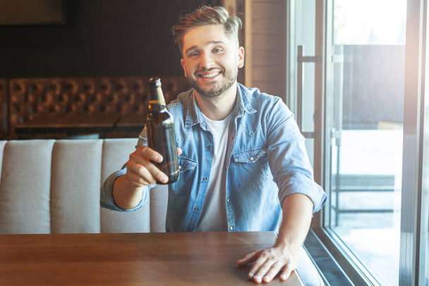 man looking at the camera and holding beer in the hand at cafe - Foto, imagen