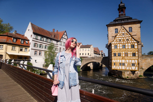Outdoor Portrait of a beautiful young confident woman posing on the street of Bamberg. Model in stylish sun glasses. Girl looks up. Women's fashion. Sunny day. Urban lifestyle. Copy space for text - Fotó, kép