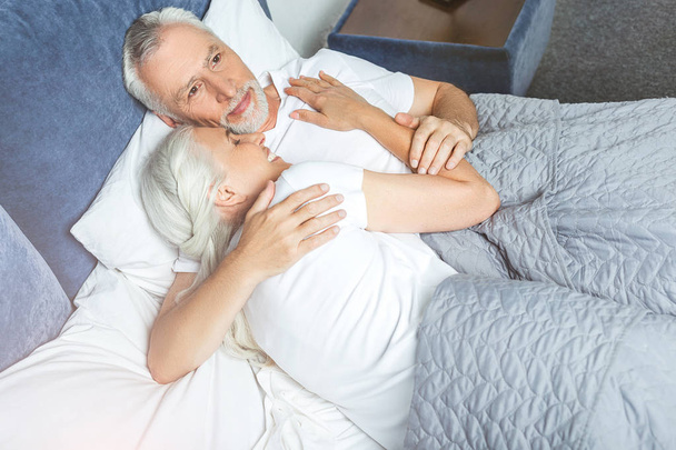 man hugging woman sleeping on his shoulder in the bed - 写真・画像