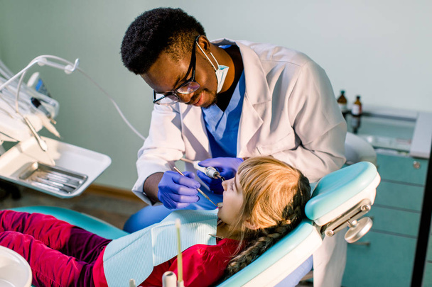 Close up portrait of a little smiling girl at African-American dentist office - Фото, зображення