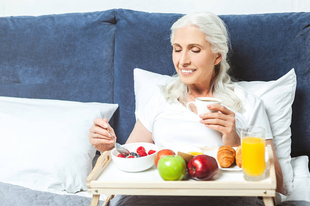 portrait of senior woman having breakfast in the bed at the morning - Foto, immagini