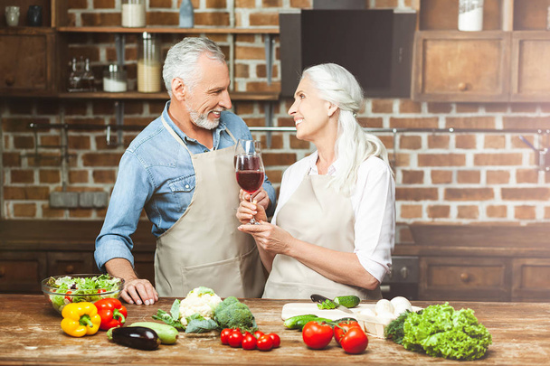 couple drinking red wine while cooking at the kitchen - Photo, Image