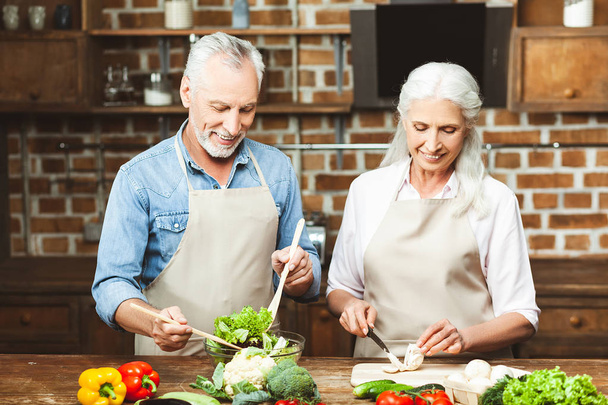 portrait of happy couple preparing salad at the kitchen together - Photo, image