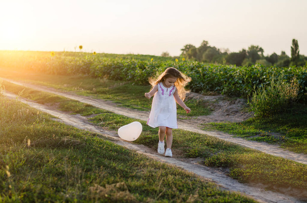 Dziewczynka z balonem biały serca w polu na łące. Koncepcja Happy Valentines Day i dzień matki. Nieostrość - Zdjęcie, obraz