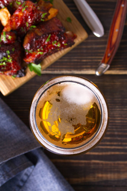 Glass of beer and grilled pork spare ribs with fry, tasty snack to beer. Beer and food concept. Ale and meat. View from above, top studio shot  - Фото, изображение