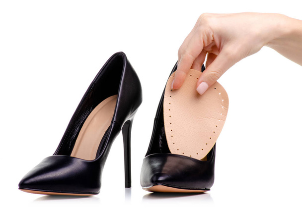 Female black leather high heels shoes insole in hand on white background isolation - Zdjęcie, obraz