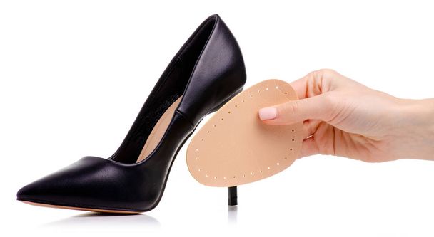 Female black leather high heels shoes insole in hand on white background isolation - Foto, afbeelding