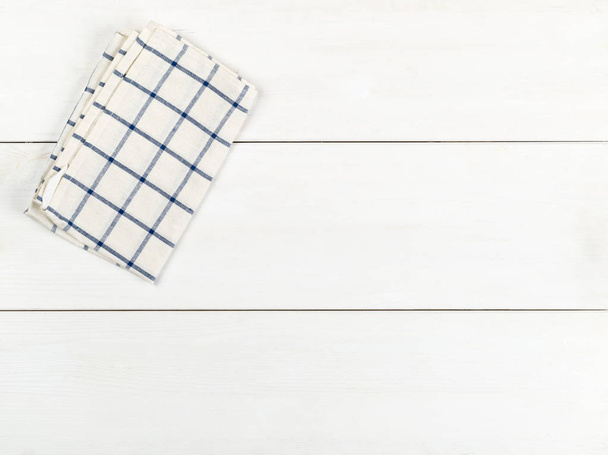 Blue and white checkered dishcloth on white wooden plank table flat lay top view from above with copy space - Fotoğraf, Görsel