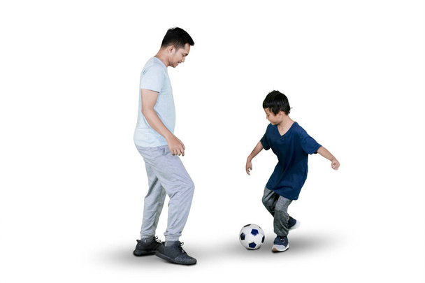 Image of little boy playing football with his father in the studio, isolated on white background - Φωτογραφία, εικόνα