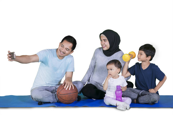 Picture of Muslim family taking selfie picture together after doing exercises while sitting in the studio - 写真・画像