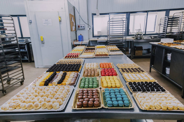 mnoho různých sladké pokrmy připravené na kovový stůl továrnu na výrobu potravin - Fotografie, Obrázek