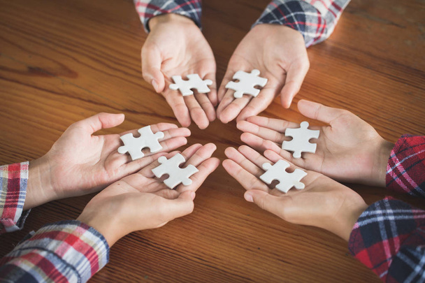 Geschäftsleute Holding Jigsaw Puzzle, Gruppe von Geschäftsleuten, die ein Puzzle verwenden, um die Notwendigkeit zu demonstrieren, in die gleiche Richtung zu arbeiten, um vollständig und effektiv zu arbeiten - Foto, Bild