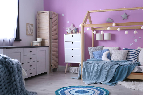 Child's room interior with comfortable bed and garland - Foto, Imagen