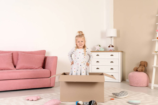 Linda niña jugando con caja de cartón en casa
 - Foto, imagen