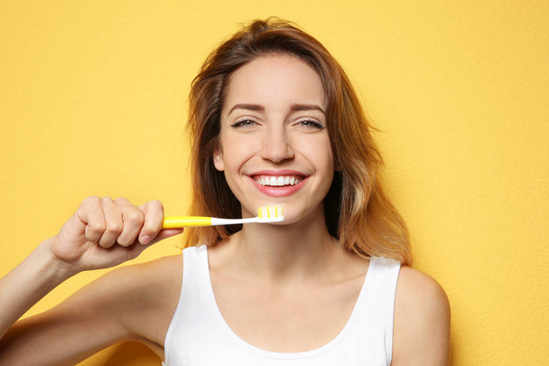 Portrait of young woman with toothbrush on color background - Foto, afbeelding