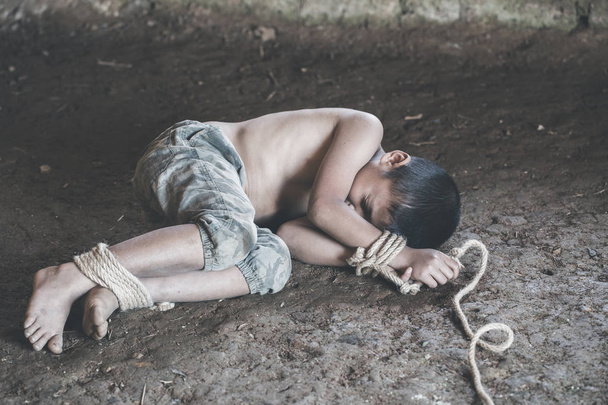 The boy was tied at the corner of the abandoned house, Stop violence against children and trafficking. - Foto, afbeelding