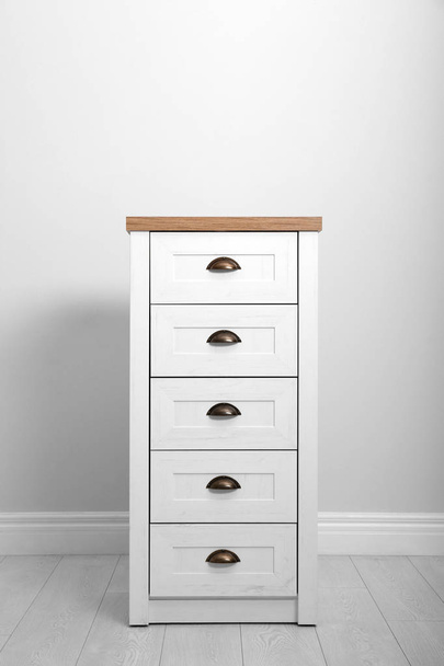 Stylish chest of drawers near white wall. Furniture for wardrobe room - Fotografie, Obrázek