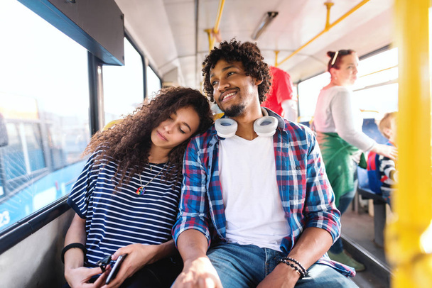 Pareja sentada y montando en el autobús de la ciudad. Chica durmiendo y apoyando la cabeza en el hombro de su novio
. - Foto, imagen