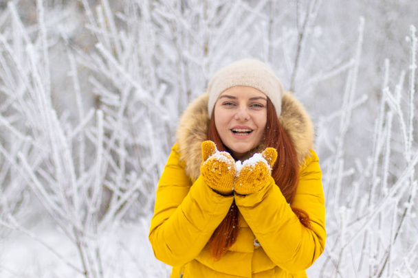 Chica feliz en ropa de invierno soplando en las palmas
 - Foto, imagen