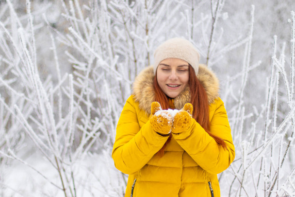 ευτυχισμένος κορίτσι σε ρούχα χειμώνα που φυσά στις παλάμες - Φωτογραφία, εικόνα