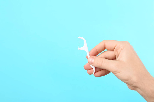 Woman holding dental floss pick on color background, space for text. Mouth and teeth care - Fotografie, Obrázek