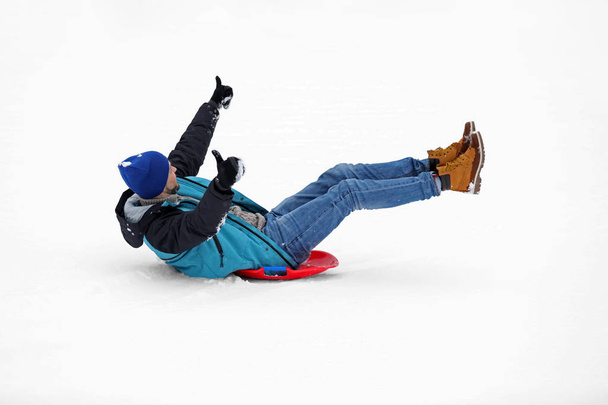 Man sliding on sled outdoors. Winter vacation - Фото, зображення
