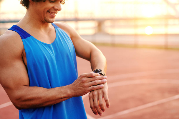 Close up of sporty man adjusting smart watch while standing on the court in the morning. - Fotoğraf, Görsel
