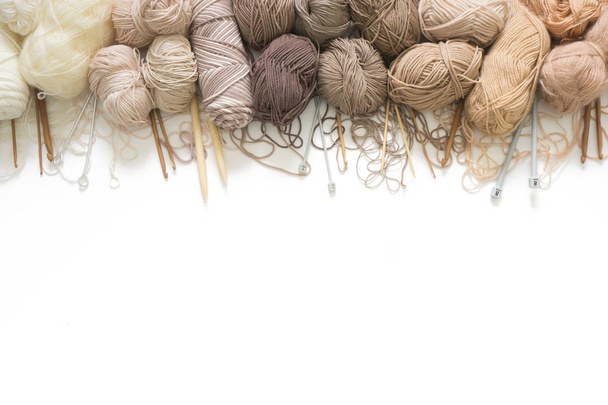 The yarn is beige, brown, gray and white. Knitting needles, scissors, knitting, knitted fabric. - Foto, afbeelding