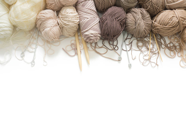 The yarn is beige, brown, gray and white. Knitting needles, scissors, knitting, knitted fabric. - Valokuva, kuva