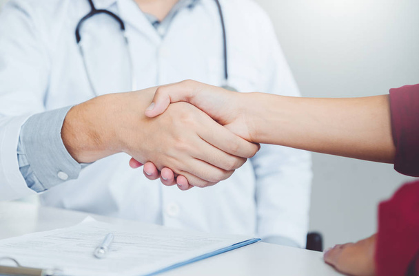 Médico de confianza estrechando la mano con los pacientes hablan en el hospital
 - Foto, imagen