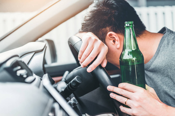 Drunk man driving a car on the road holding bottle beer Dangerous drunk driving concept - Photo, Image