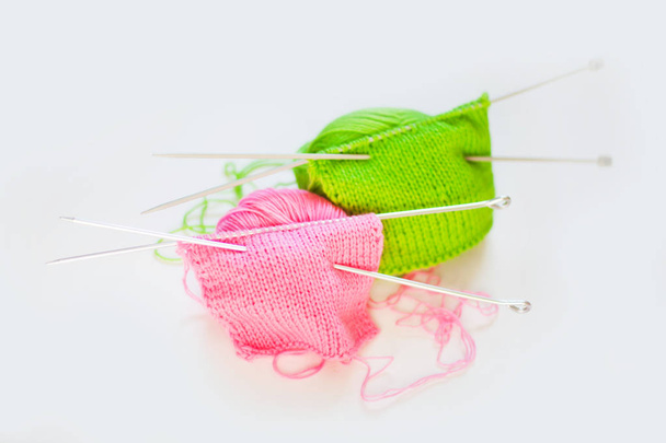 Knitted fabric of green and pink. Yarn for knitting green and pink. White background. - Foto, afbeelding