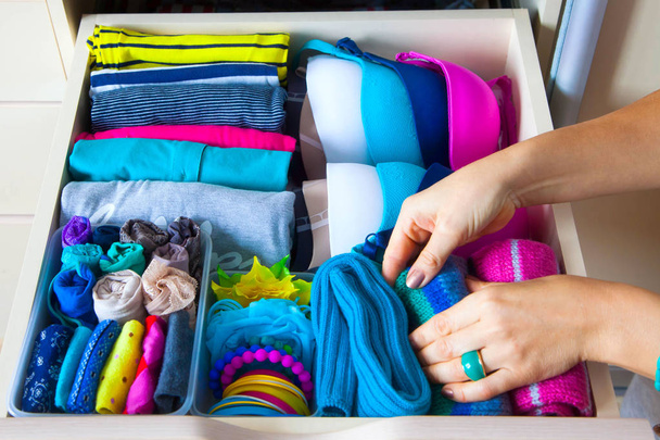 Neatly folded clothes with accessories in chest of drawers - Photo, Image