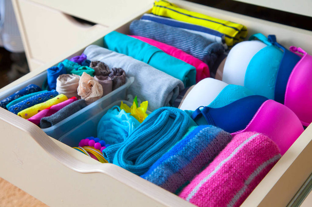 Neatly folded clothes with accessories in chest of drawers - Foto, Bild
