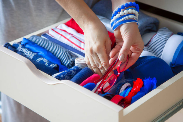 Neatly folded clothes with accessories in chest of drawers. Marine clothing style - 写真・画像