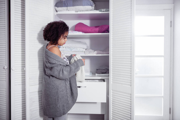 African American curly woman choosing clothes in her wardrobe - Fotó, kép