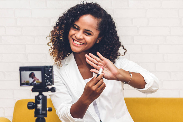 afro-americana donna blogger di fronte alla fotocamera registrazione vlog se stessa parlando con trucco cosmetici per internet social network a casa
 - Foto, immagini