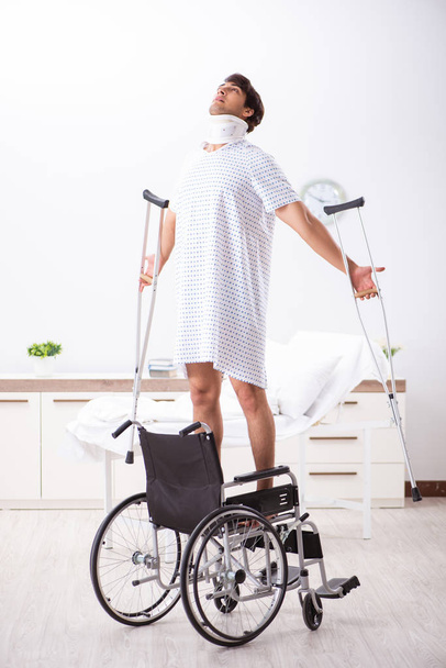 Jonge knappe man in rolstoel in het ziekenhuis  - Foto, afbeelding