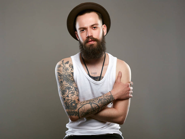 Tetovált szép szakállas ember kalapban. Brutális csípő fiú-tetoválás - Fotó, kép