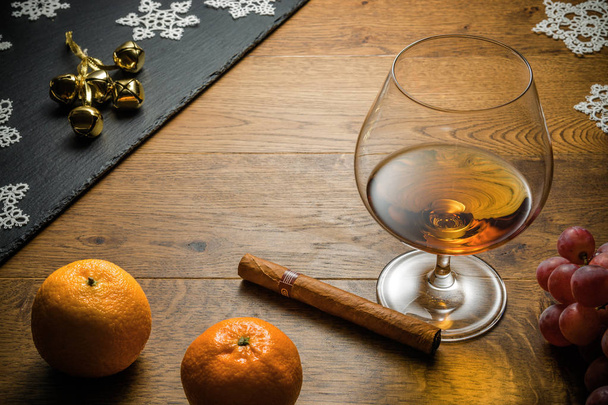 Bicchiere di cognac e sigaro con spuntino sul tavolo in legno con tagliere in pietra. Vista dall'alto con spazio di copia
 - Foto, immagini